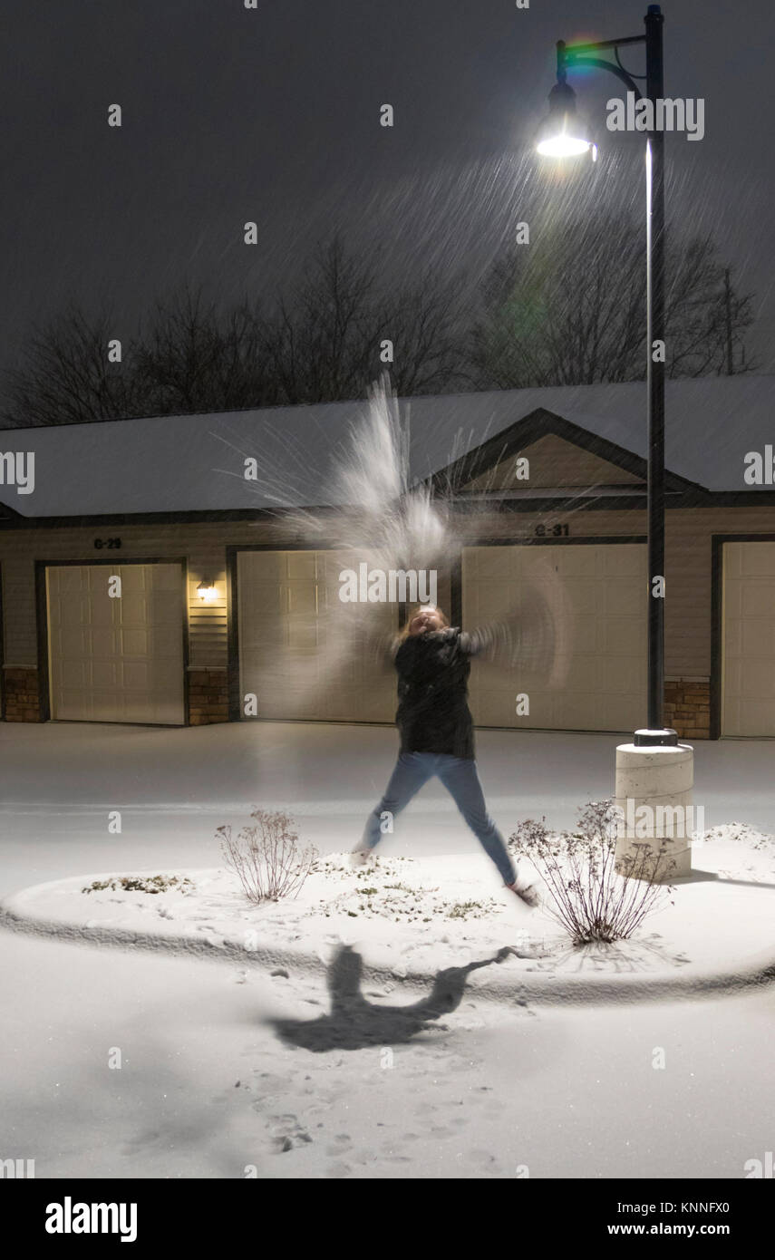 First snow: a 11-yeras old girl playing under street light as snowstorm, Ames, iowa, USA. Stock Photo