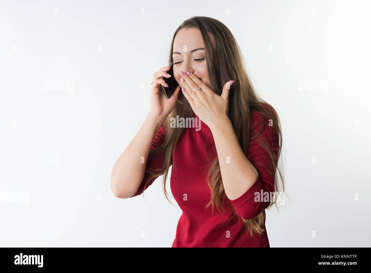 woman is speaking on her mobile phone and laughing covering her mouth with hand Stock Photo