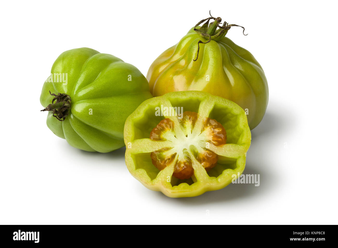 Whole and half green Coeur de boeuf tomatoes on white background Stock Photo