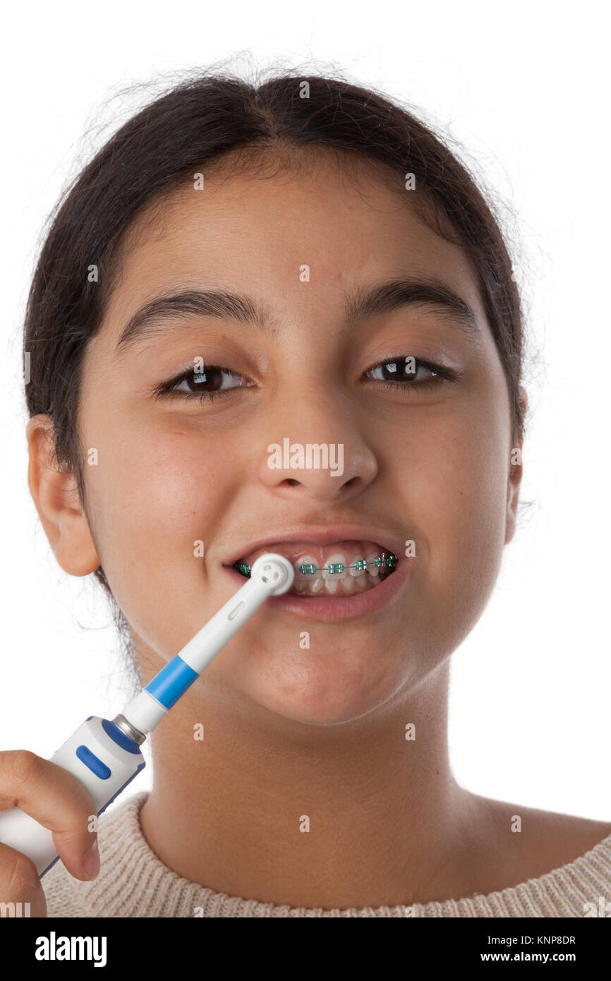 Teenage girl is brushing her teeth with dental braces with an electric