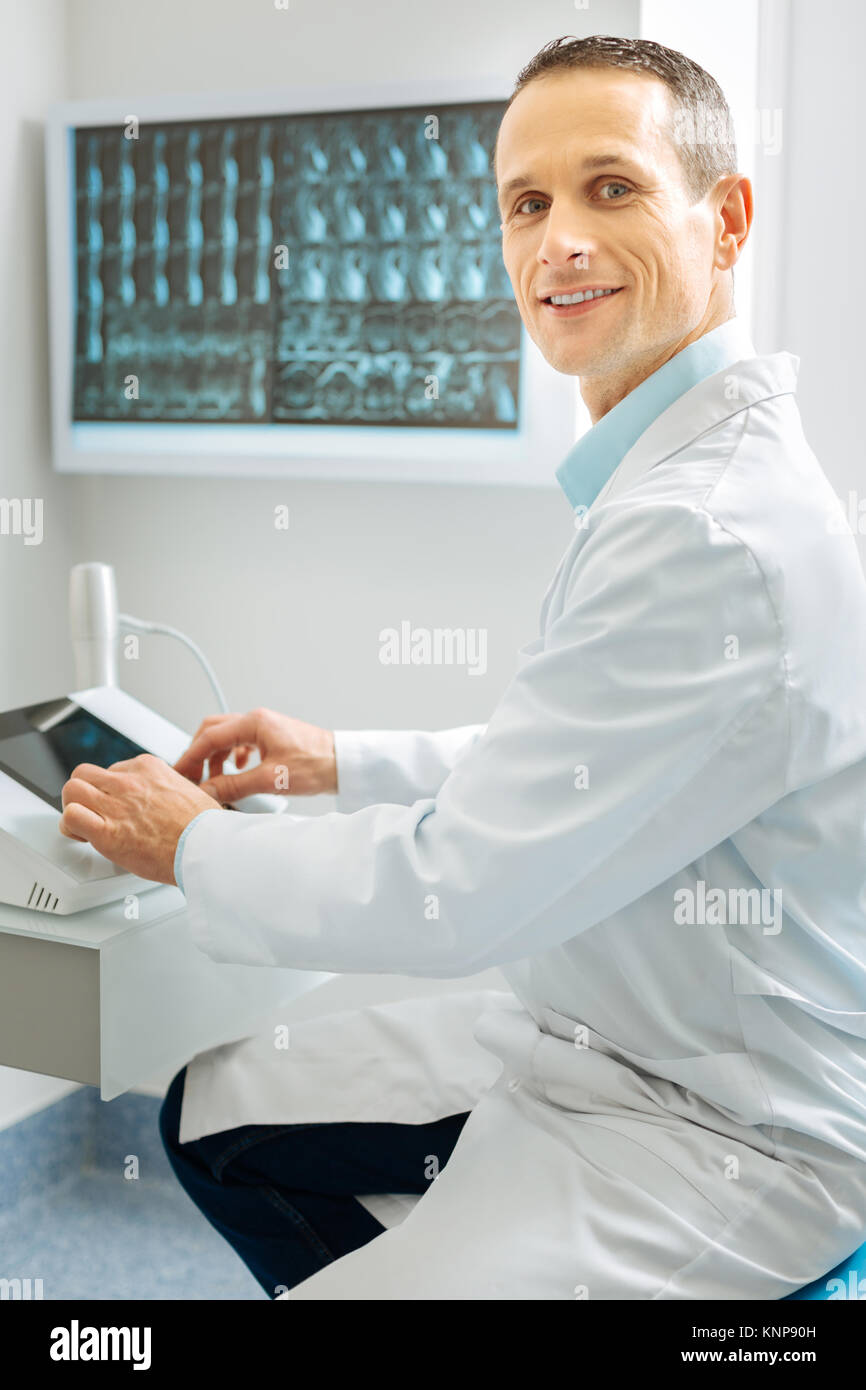 Professional male radiologist sitting near the X ray control panel ...