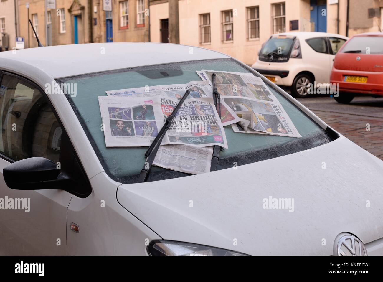 Car windscreen covered with old newspaper to prevent frost build up during cold winter weather in Scotland, UK Stock Photo