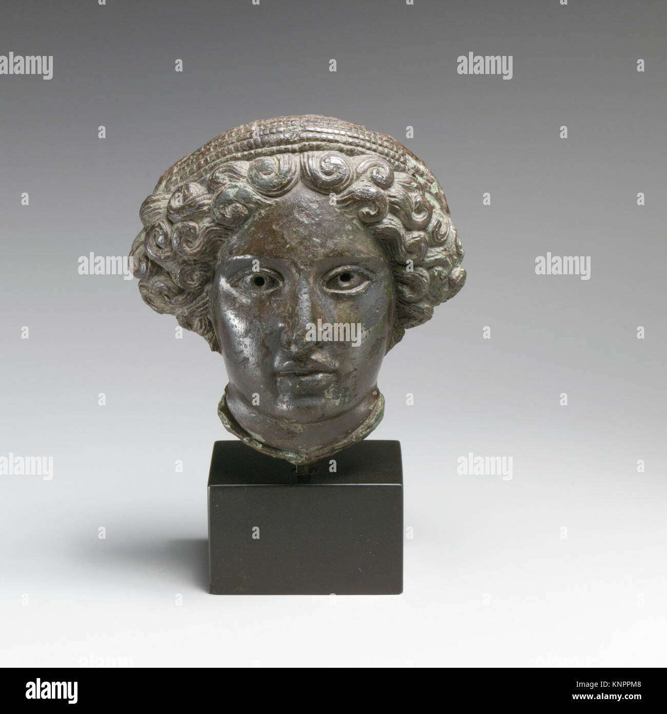 Bronze relief depicting the head of a woman, showing detailed facial ...