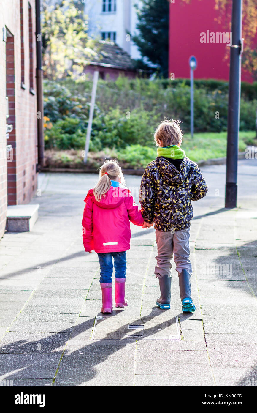 Brother and sister walking hand in hand in the streets of the city ...