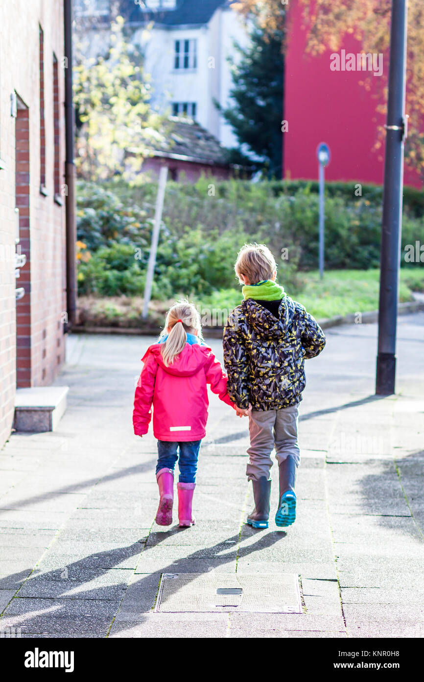Brother and sister walking hand in hand in the streets of the city ...