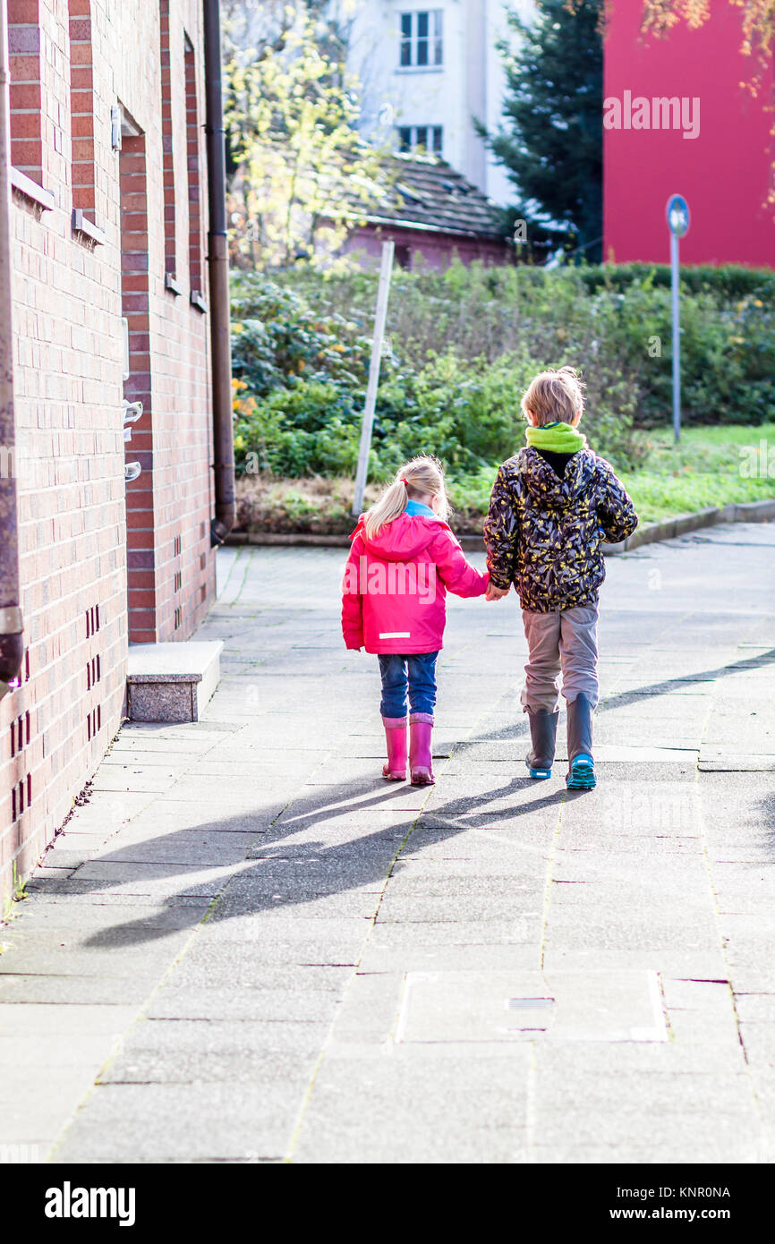 Brother and sister walking hand in hand in the streets of the city ...