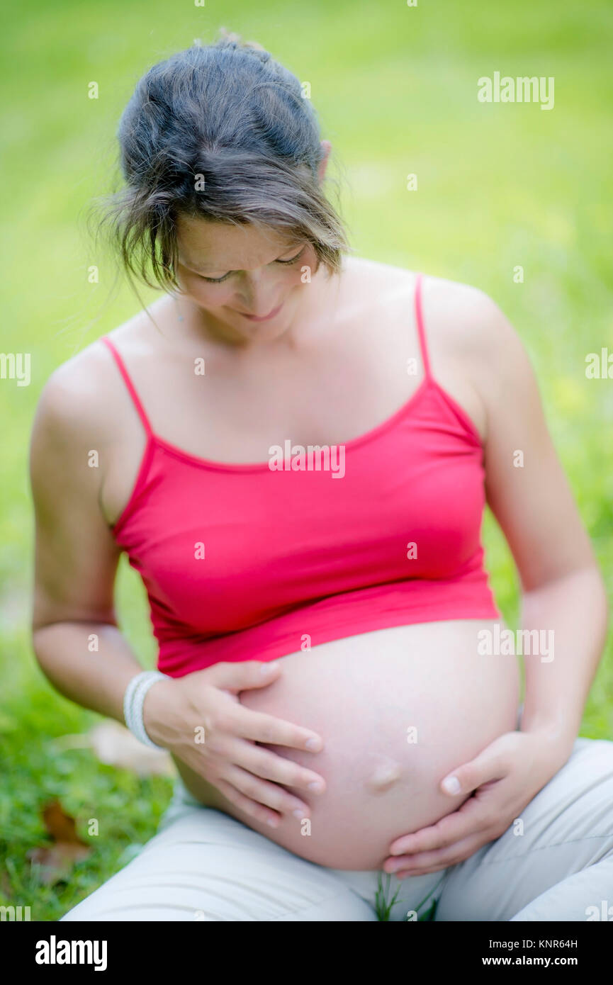 Schwangere Frau greift sich an den Babybauch - pregnant woman Stock Photo
