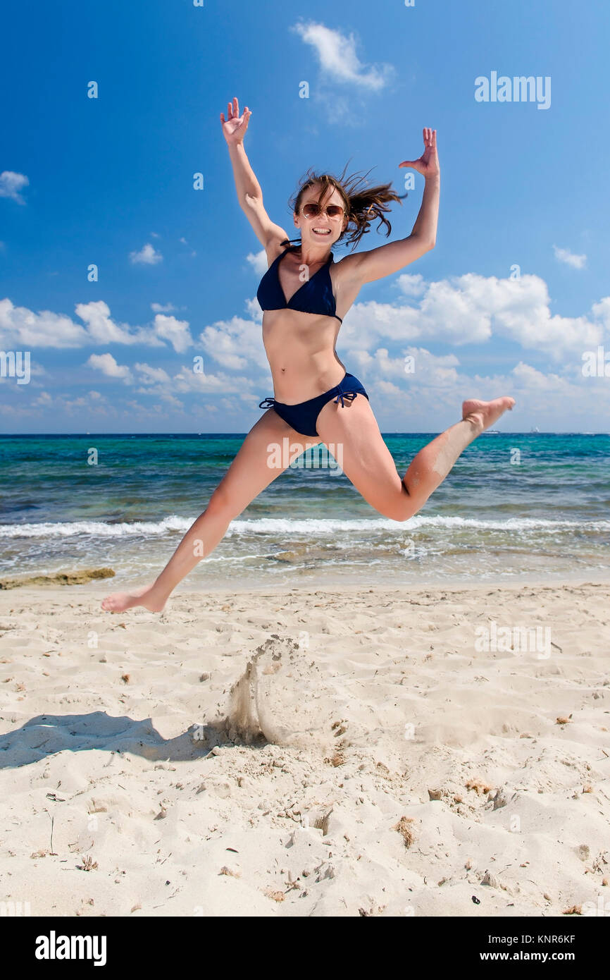Frau im Bikini springend am Strand, Ibiza, Spanien - woman jumping at the beach, Ibiza, Spain Stock Photo