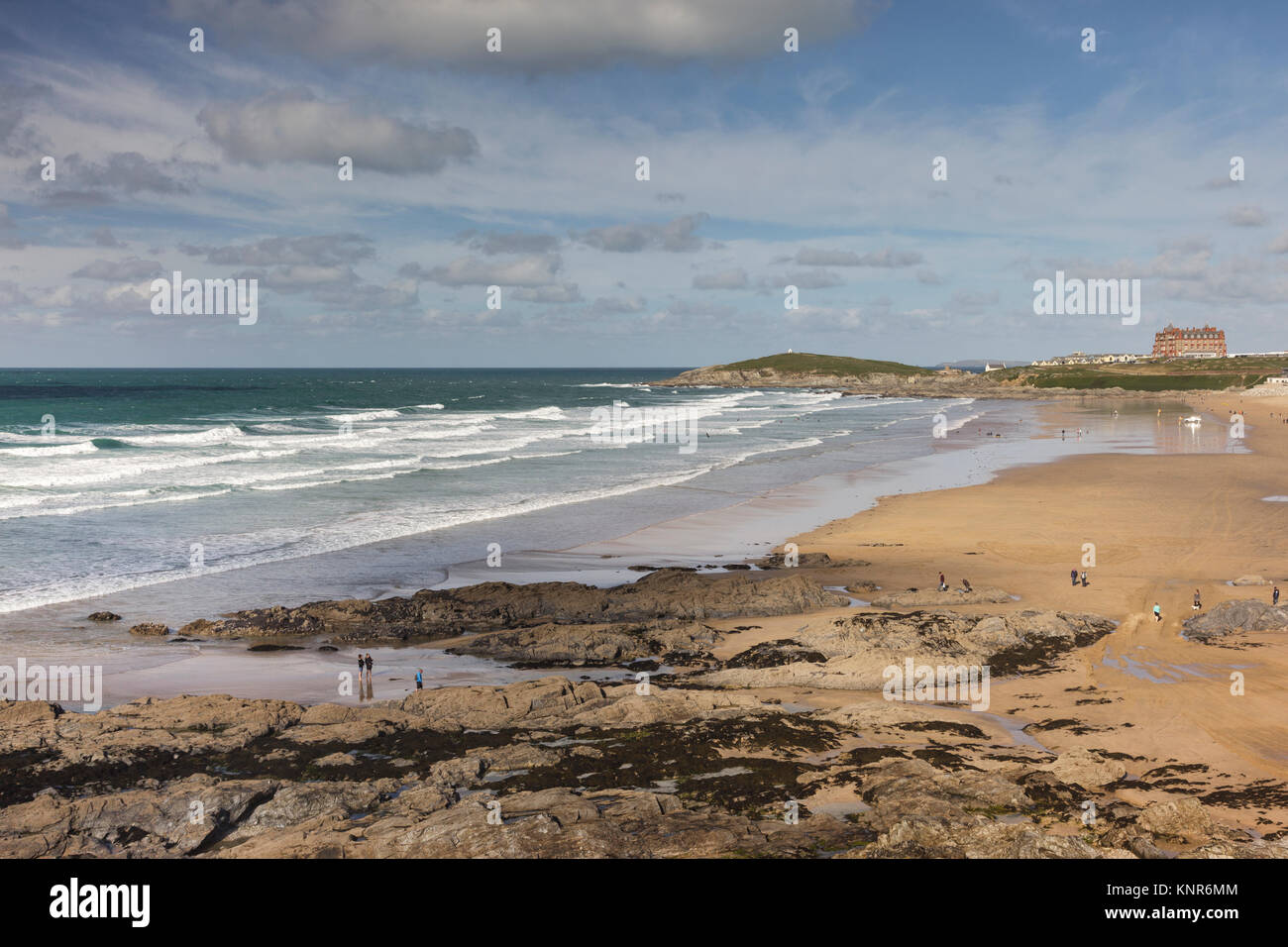 View across Fistral Beach in Newquay in Cornwall towards the Headland Hotel. Waves are breaking on the beach and surfers are in the water. Stock Photo