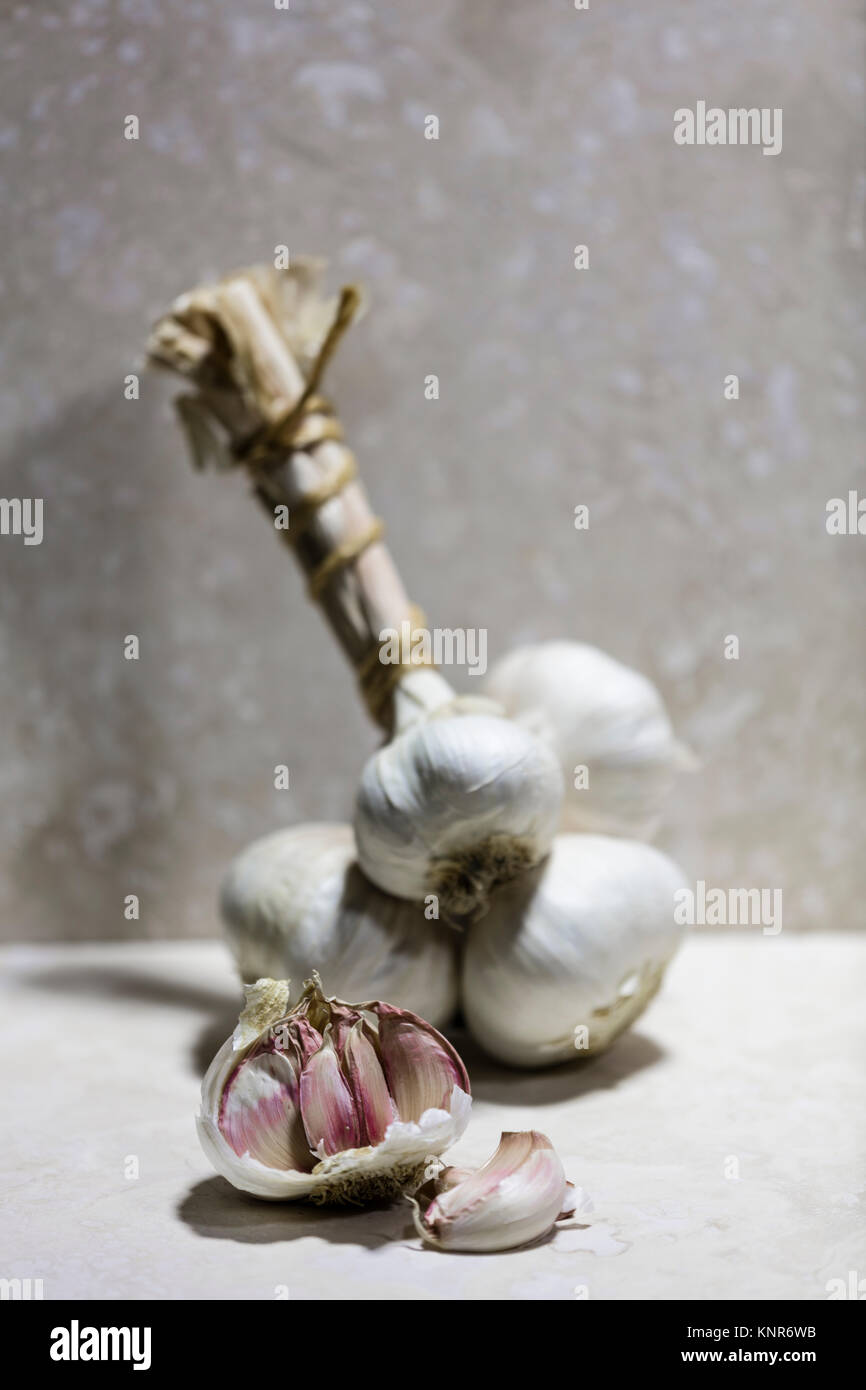 Grappe of garlic with a garlic bulb and garlic cloves on a kitchen work surface Stock Photo