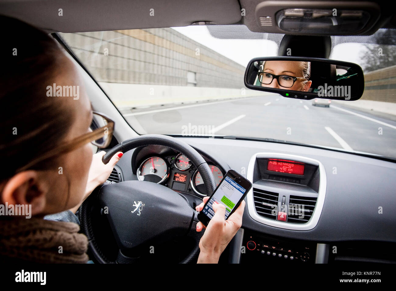 Autofahrerin mit Handy schreibt SMS - car driver with mobile phone writing sms Stock Photo