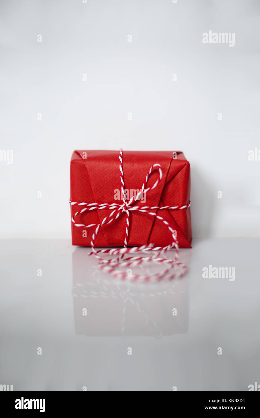 Christmas gift box wrapped in red paper and bow of dtriped rope on ...
