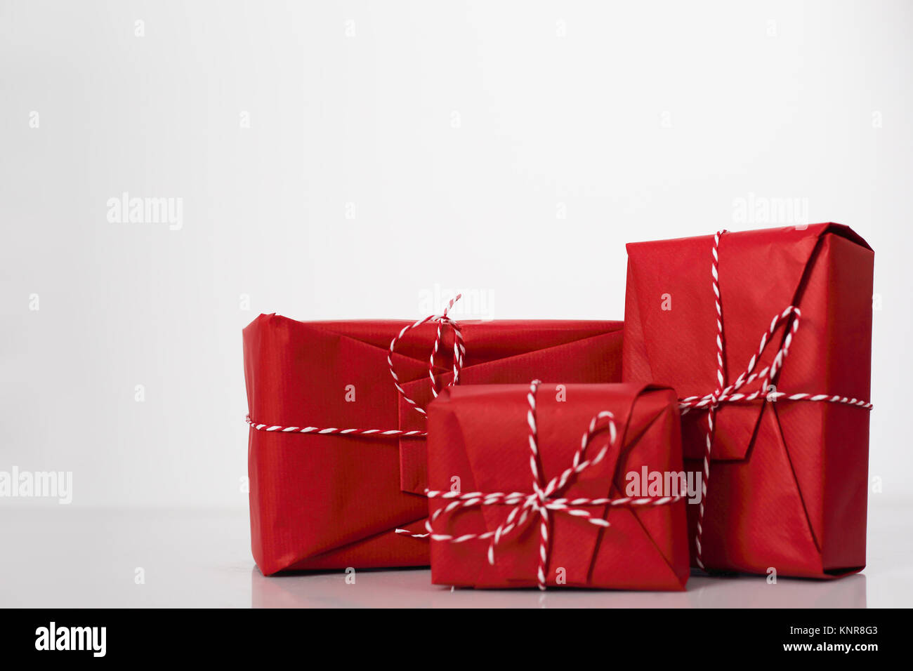 Christmas gift boxes wrapped in red paper and bow of dtriped rope on ...