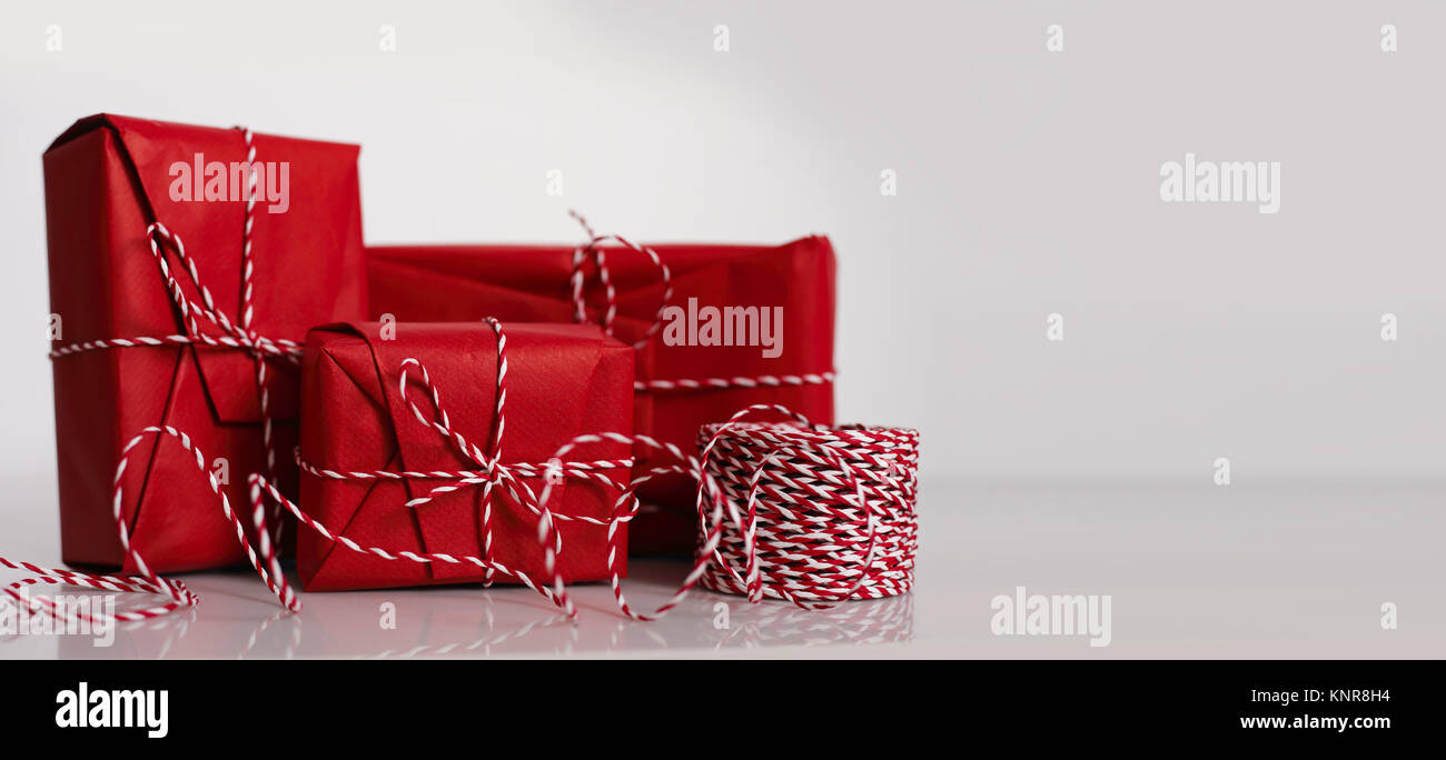 Christmas gift boxes wrapped in red paper and bow of dtriped rope on ...