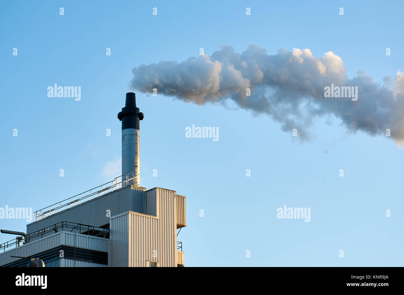 A generic factory generates air pollution by releasing a smoke into the air. Stock Photo