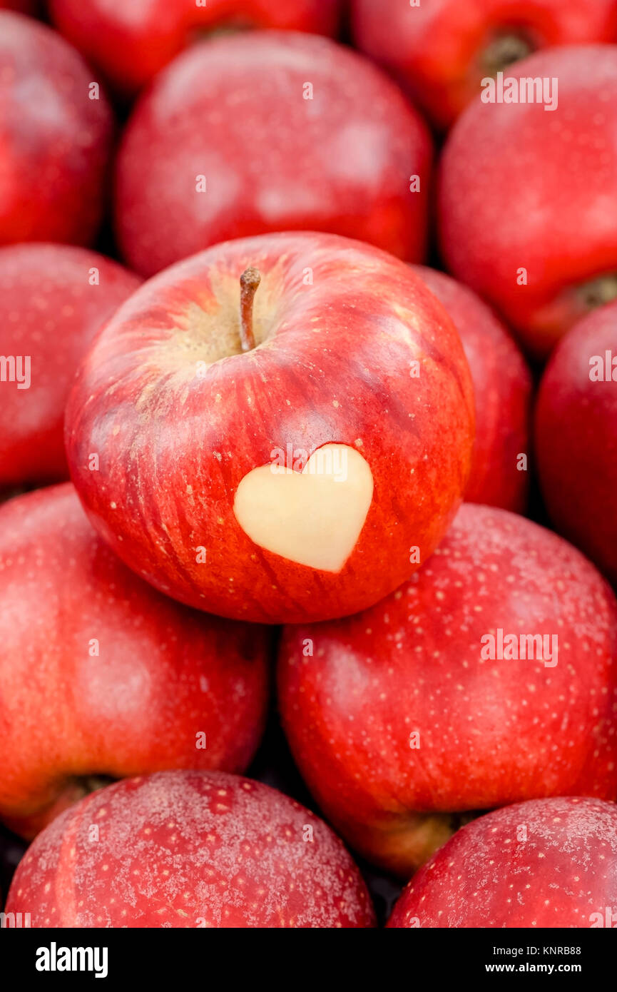Roter Apfel mit Herz liegt auf roten ƒpfeln - red apples with heart Stock Photo