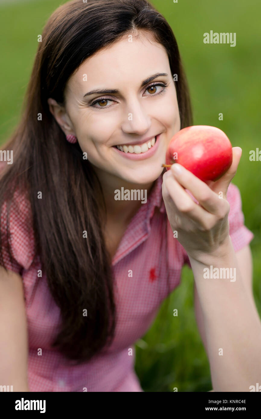 Junge Frau mit Apfel in der Wiese - woman with apple in meadow Stock Photo