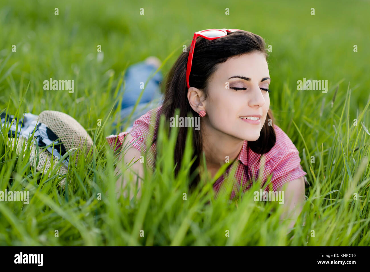 Junge Frau liegt in der Fruehlingswiese - Young woman relaxing on the spring meadow Stock Photo