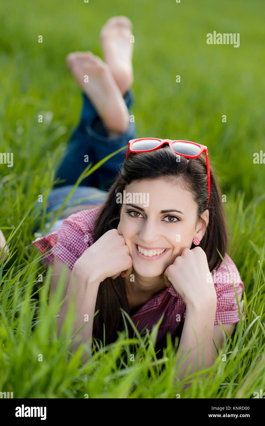 Junge Frau liegt in der Fruehlingswiese - Young woman relaxing on the spring meadow Stock Photo