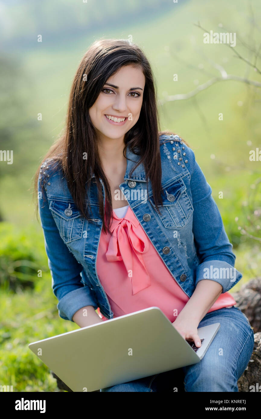 Junge Frau sitzt mit Laptop in der Natur - woman with laptop in nature Stock Photo