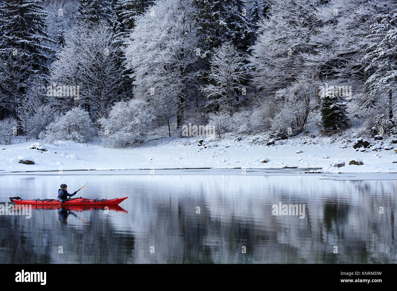 Woman in a red kayak paddling in winter wanderland on a cold winter day at  Lago di Predil, Alps, Italy Stock Photo - Alamy
