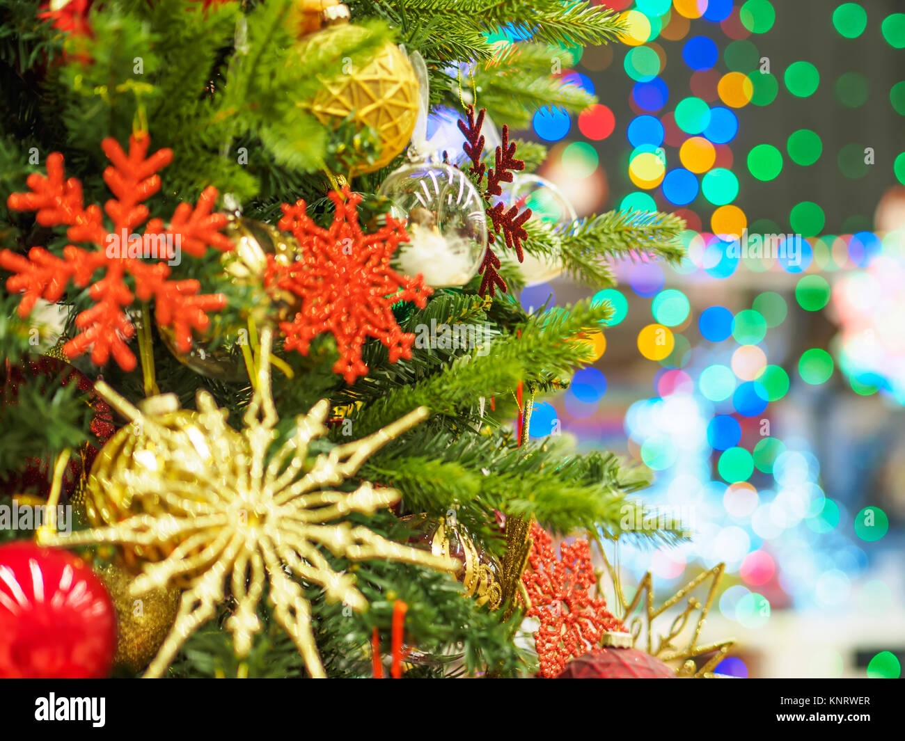 Bright and beautifully decorated with toys Christmas tree against shiny ...