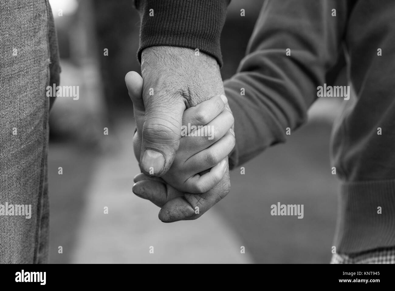 Old and young holding hands black and white Stock Photo