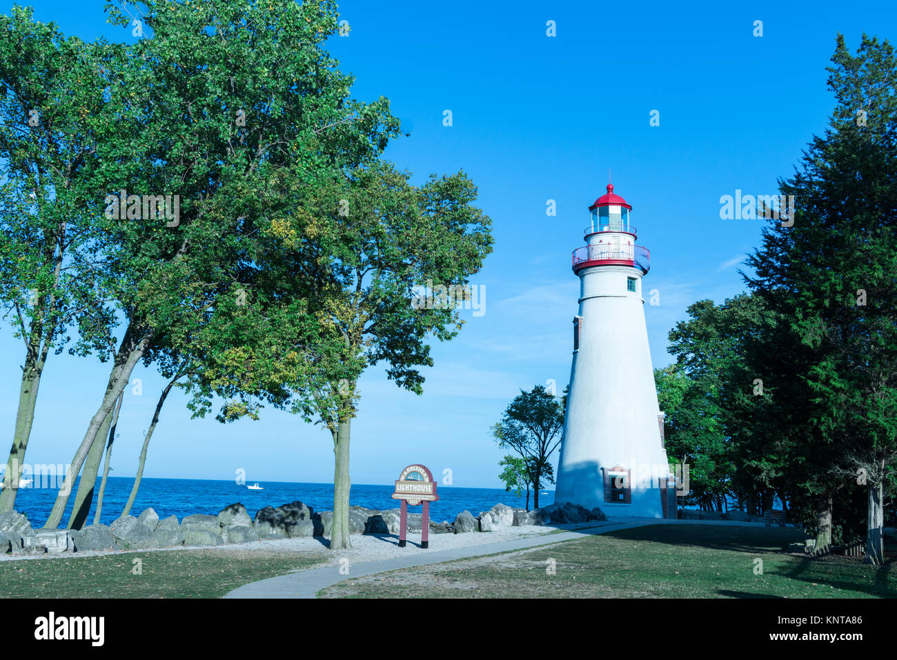 Marvel at lighthouse shot during the day with boats in the background. Stock Photo