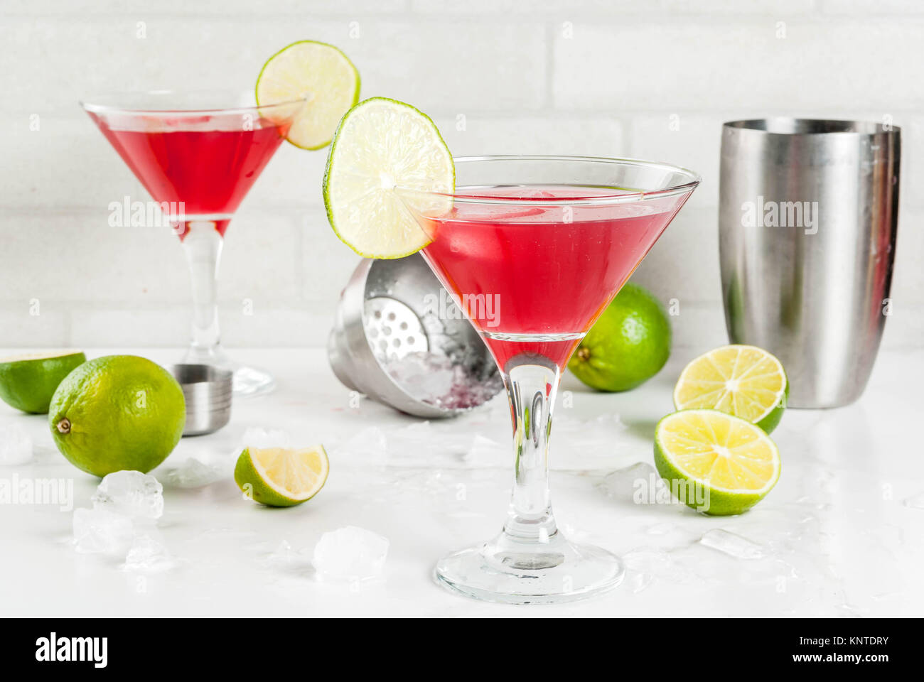 Red cosmopolitan cocktail with lime in martini glass, on white marble ...