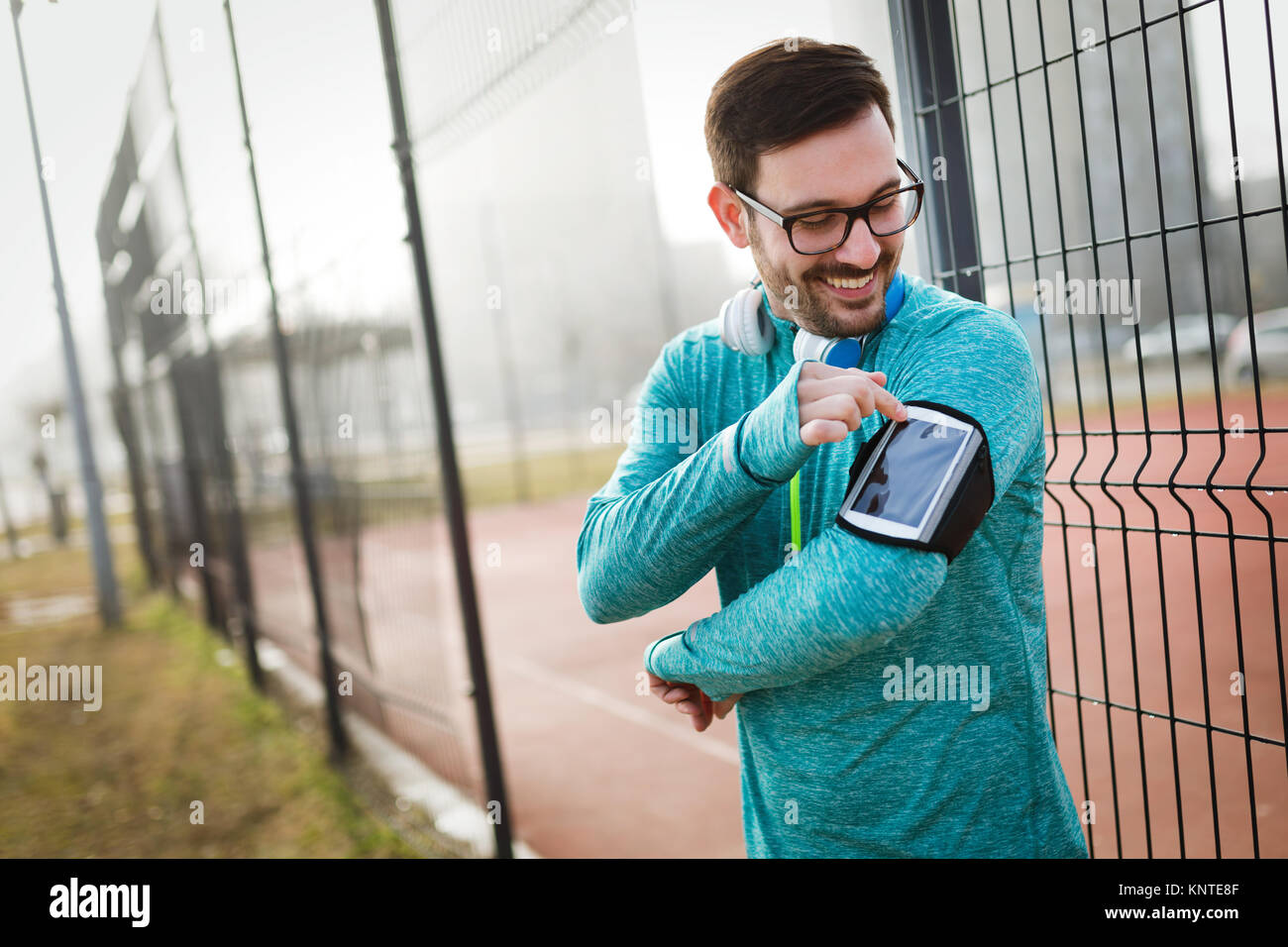 Sportsman using phone to listen to music while running and joggi Stock Photo
