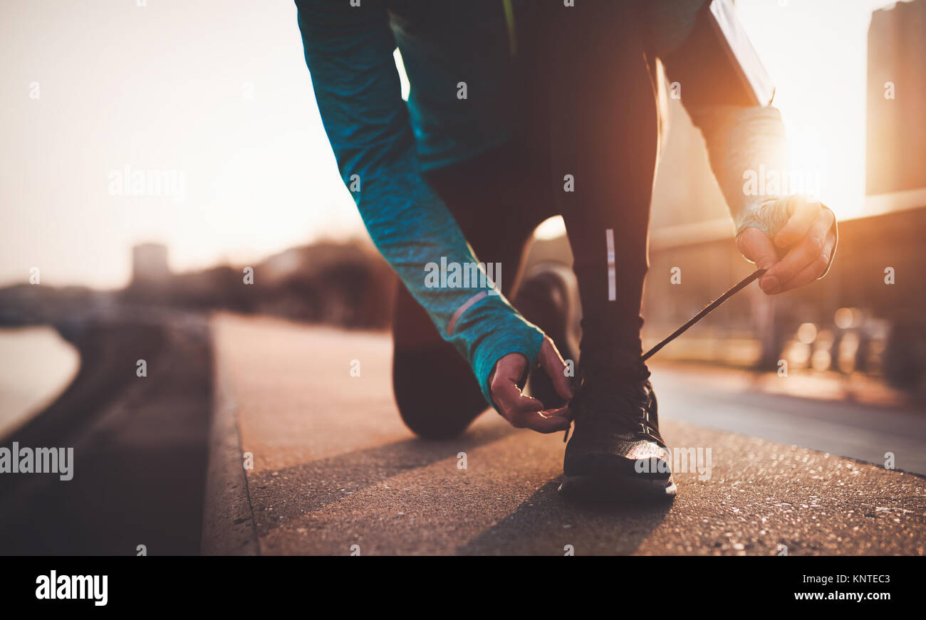 Sportsman tying shoelaces after jogging exercises Stock Photo