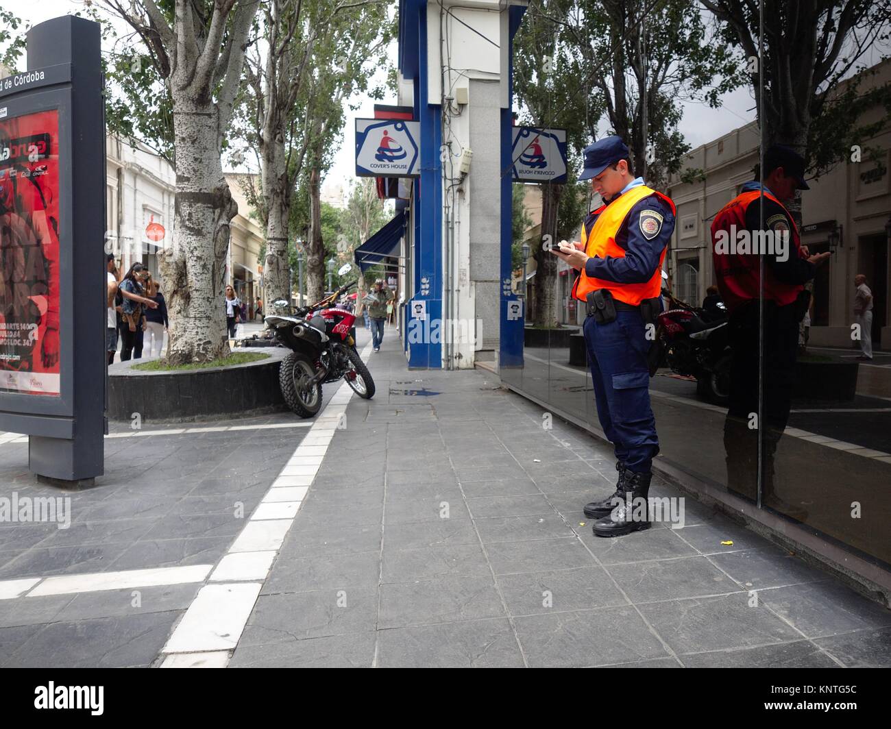 Cordoba, Argentina - 2017: An on duty police officer appears to be distracted on his cellular phone. Stock Photo