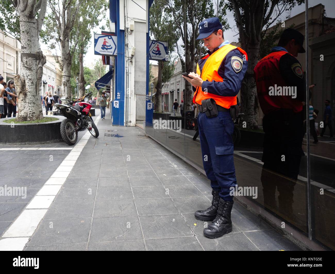 Cordoba, Argentina - 2017: An on duty police officer appears to be distracted on his cellular phone. Stock Photo