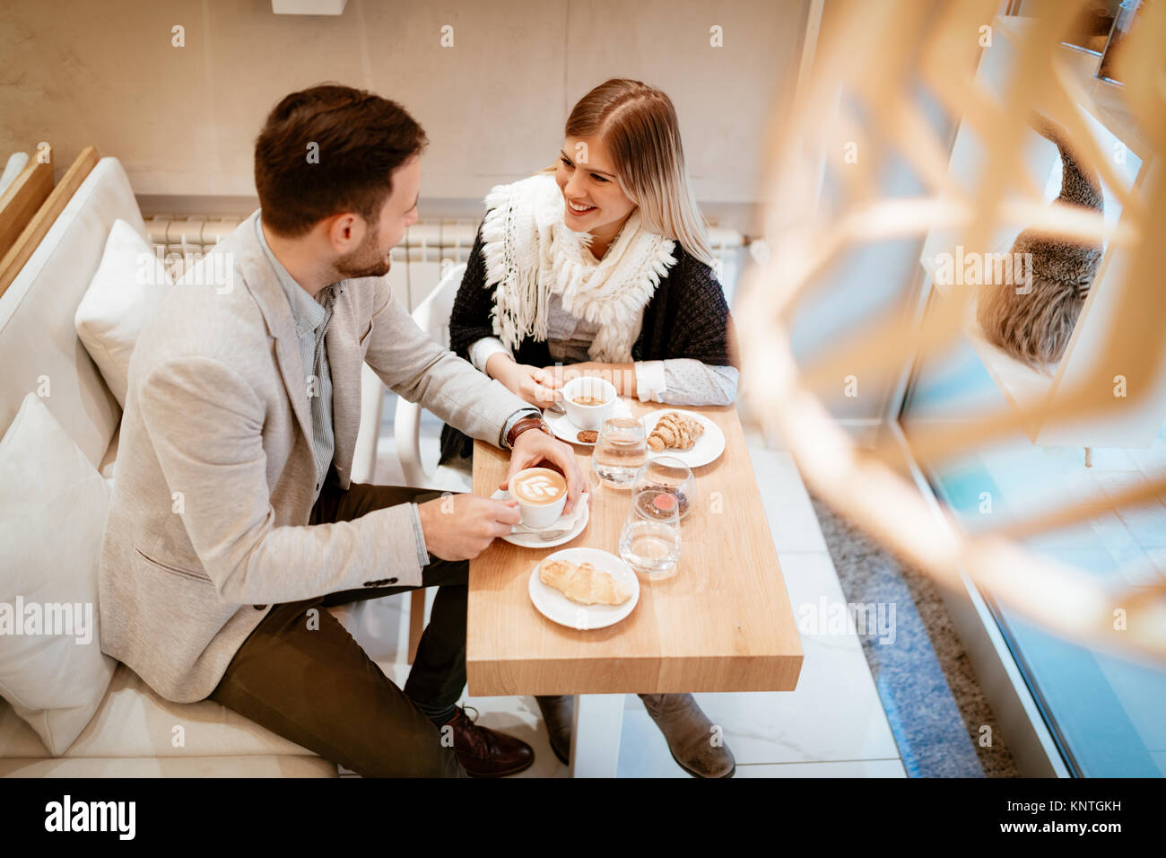 Young man and young woman sitting at cafe and talking with smile. They ...