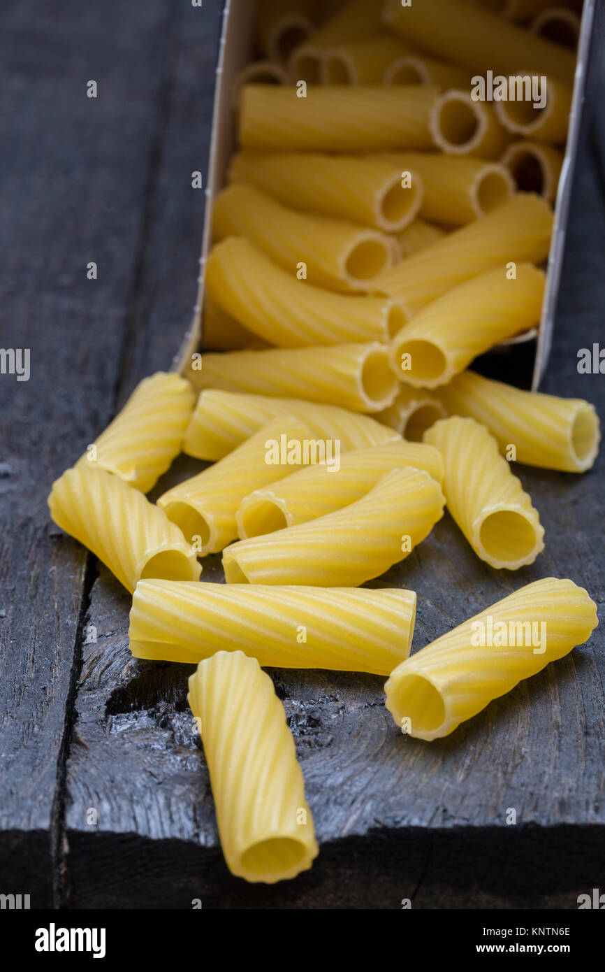 Tortiglioni noodle on dark rustic wood. Stock Photo