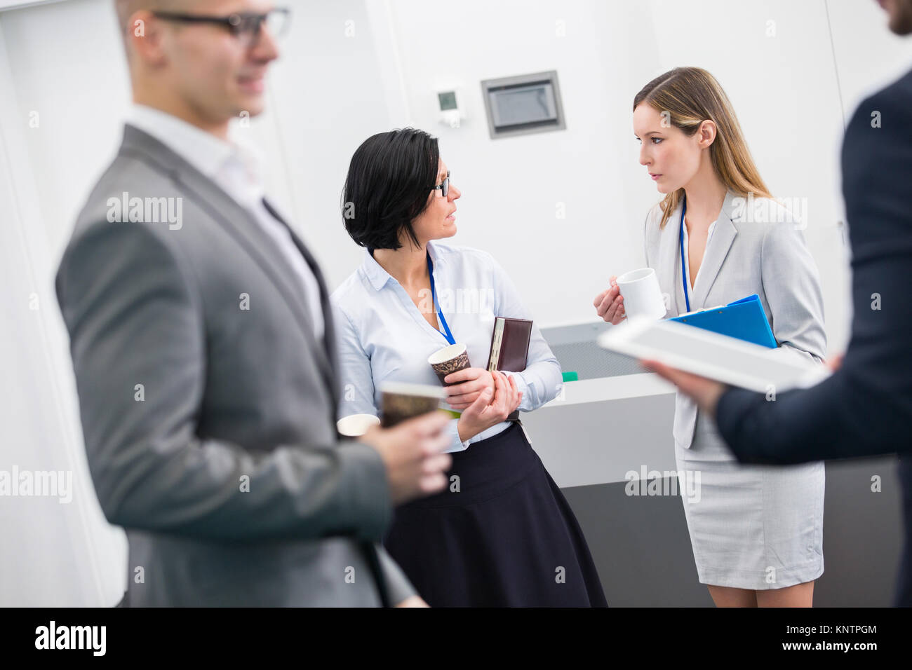 Female professionals communicating while standing in seminar hall Stock Photo