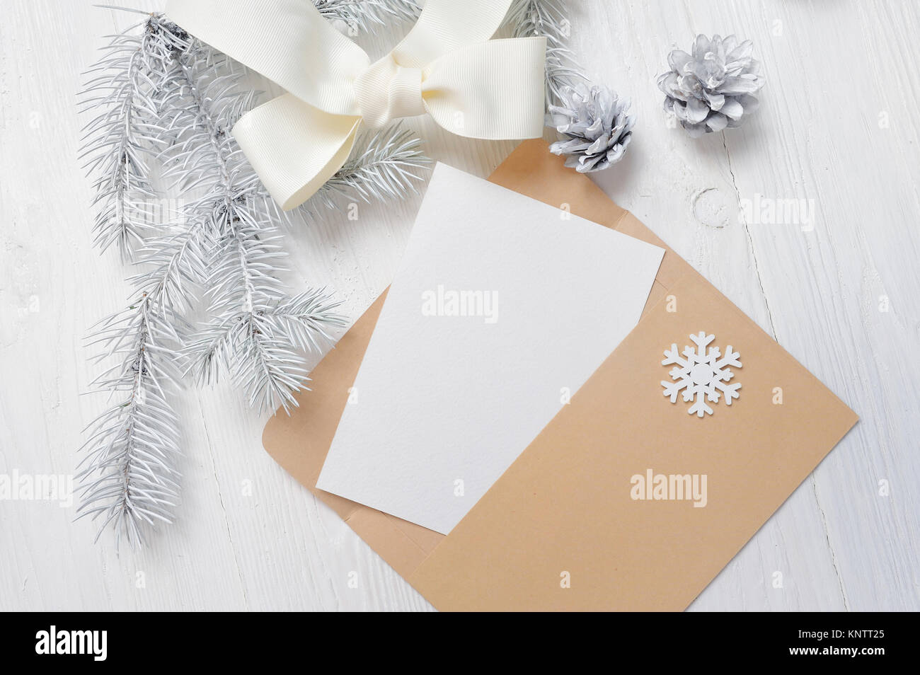 Mockup Christmas greeting card letter in envelope with white tree and cone, flatlay on a wooden background, with place for your text Stock Photo