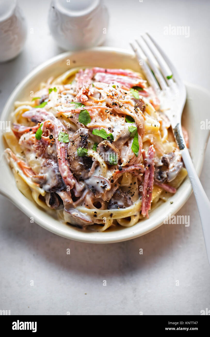 Tagliatelle ham mushroom. Pasta in cream sauce with smoked ham and roasted mushrooms Stock Photo