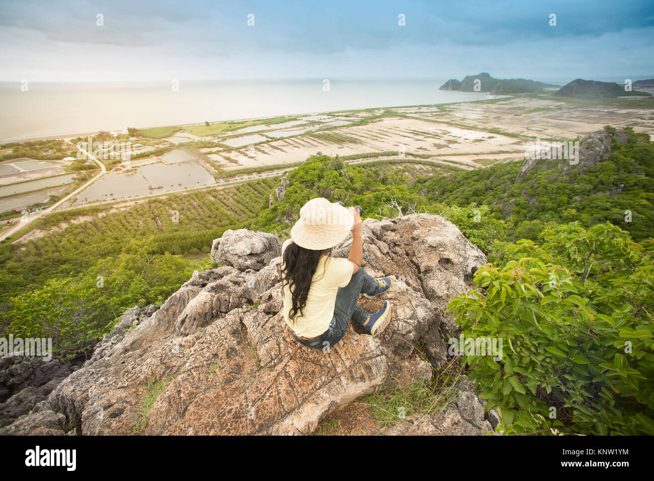 Pretty Asian woman climbing and looking a binoculars on the peak of ...
