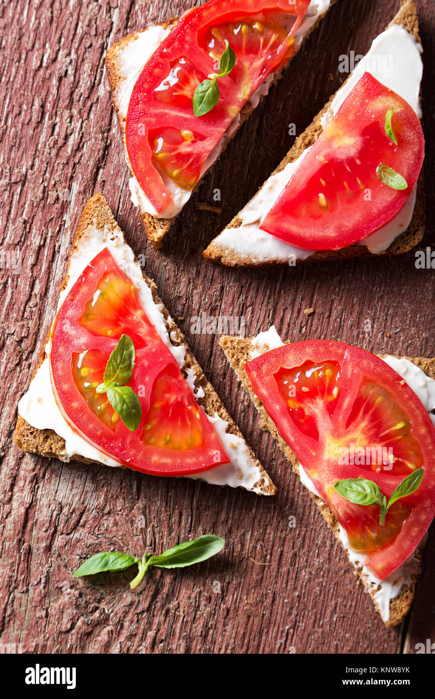 summer sandwiches with tomato and basil on a wooden surface. Stock Photo