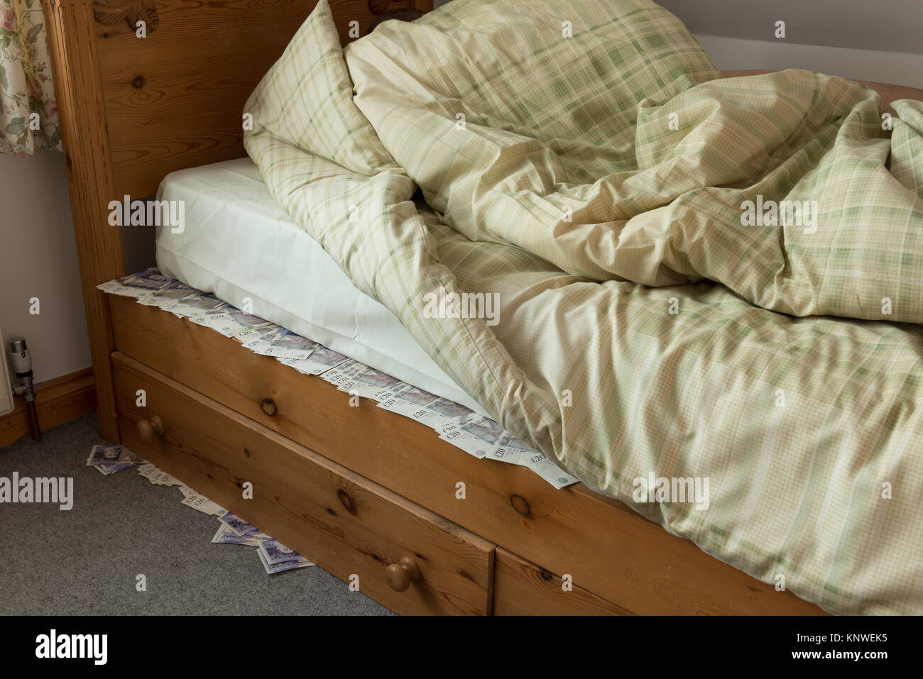 Sleeping on top of stashed cash money banknotes under the bed mattress hidden as alternative to bank or building society Stock Photo