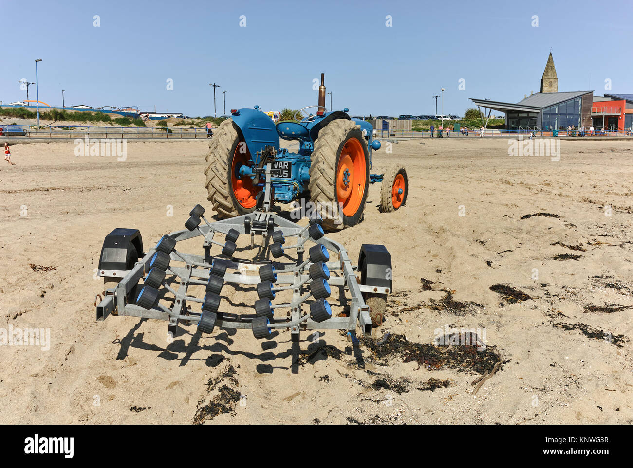 A blue tractor with a boat trailer on the sands at Newbiggin-By-The-Sea, in Northumberland, on a spring day. Stock Photo