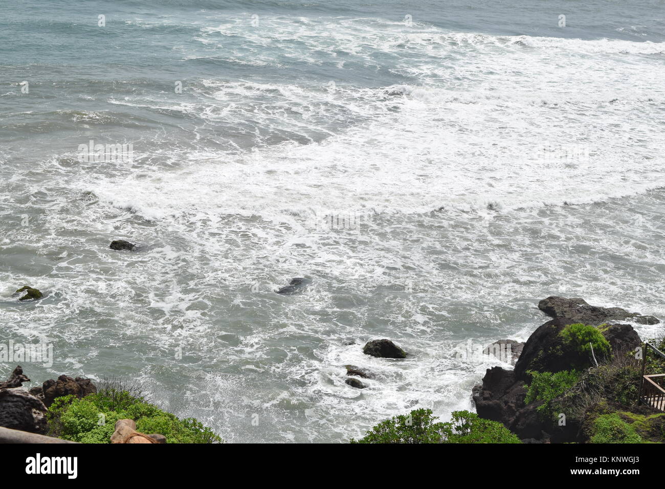 Sea view from mountain. Sea, trees and mountain. Rocky sea view with coconut trees in side. Sea surrounded by greenery and mountains. Stock Photo