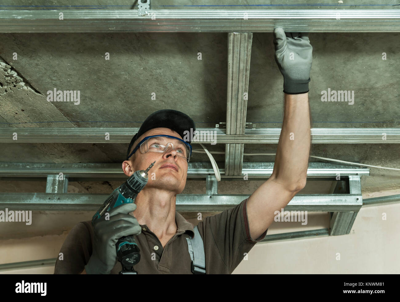 Worker assembles profile metal frame for plasterboard ceilings Stock