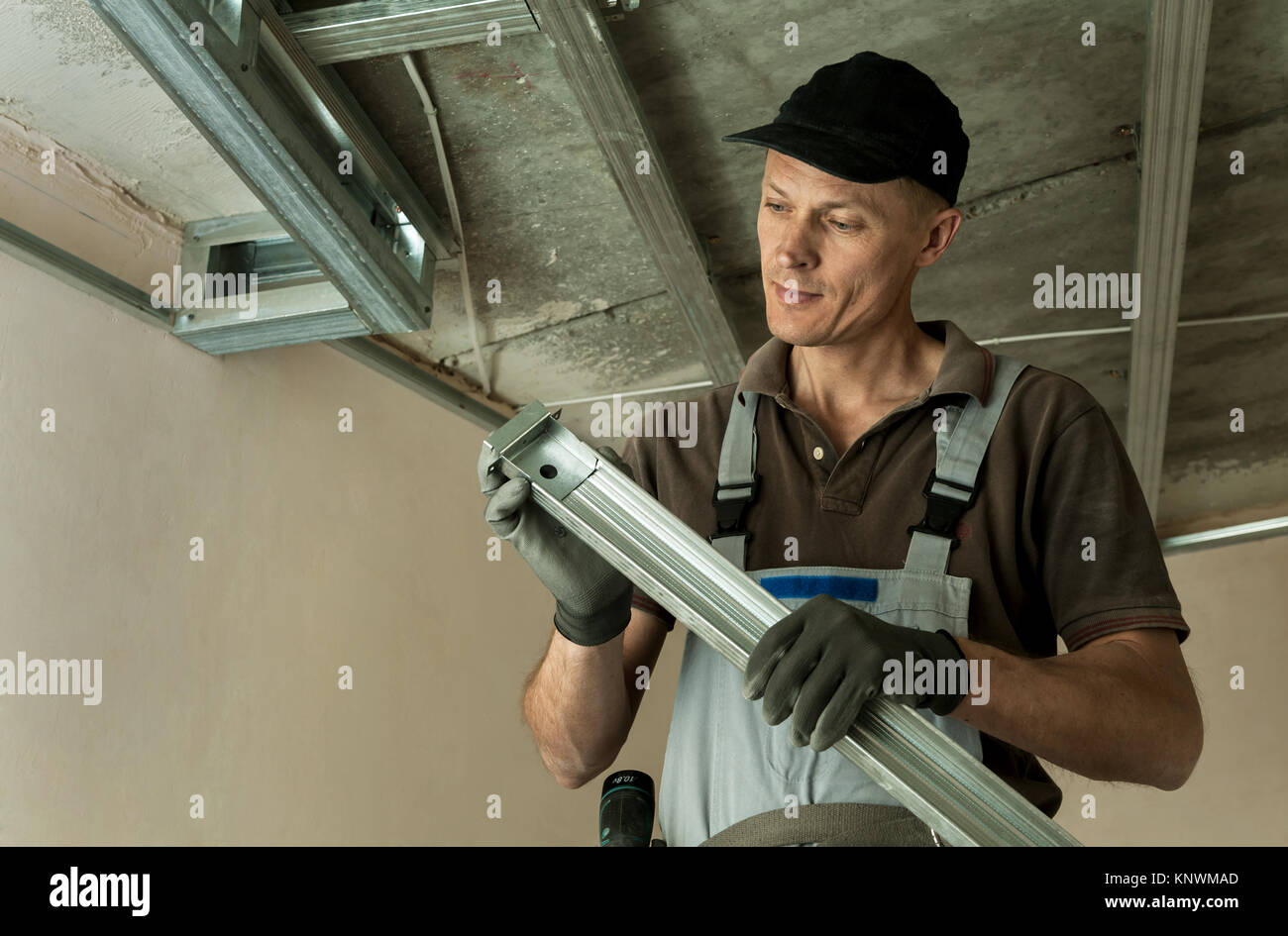 Worker assembles profile metal frame for plasterboard ceilings Stock