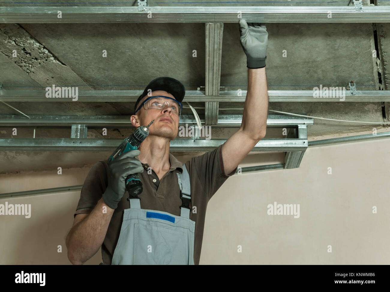Worker assembles metal frame for plasterboard ceilings Stock Photo
