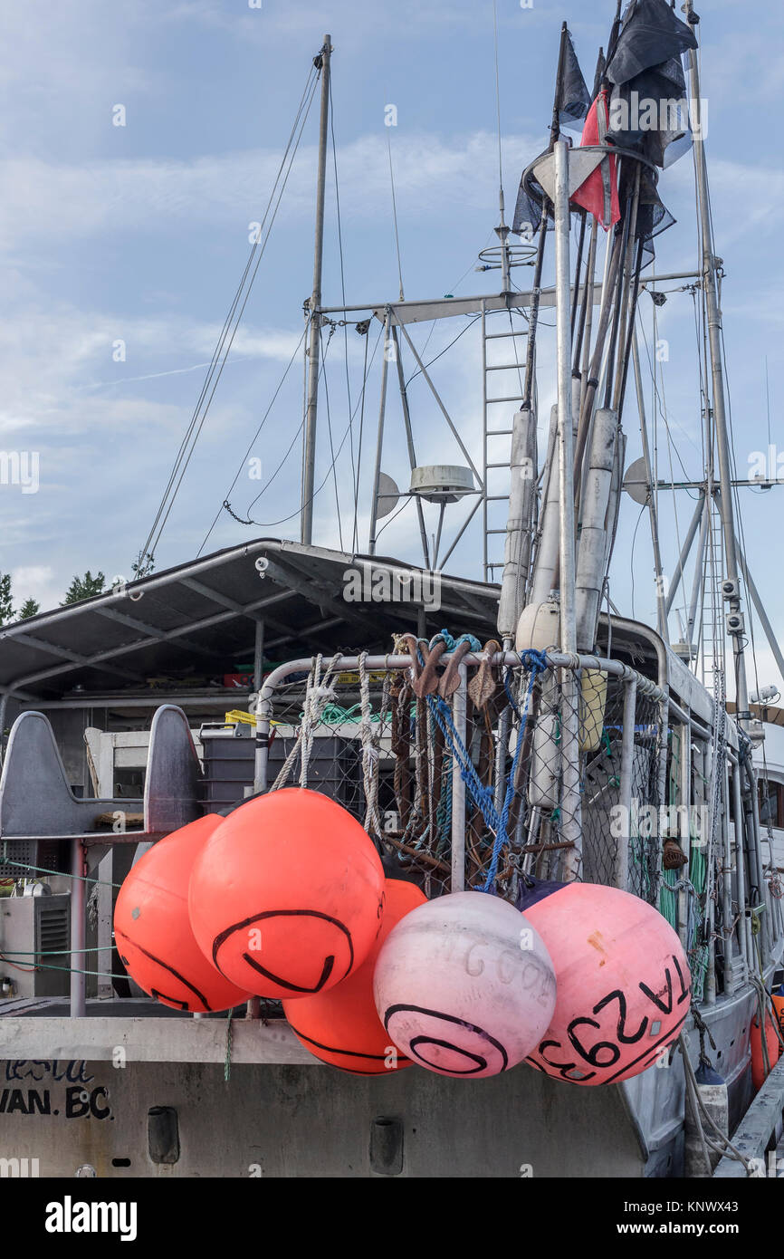Red 'scotchmen' (buoys), anchors, flags and other longline fishing gear is visible aboard a commercial halibut fishing boat docked in Port Hardy. Stock Photo
