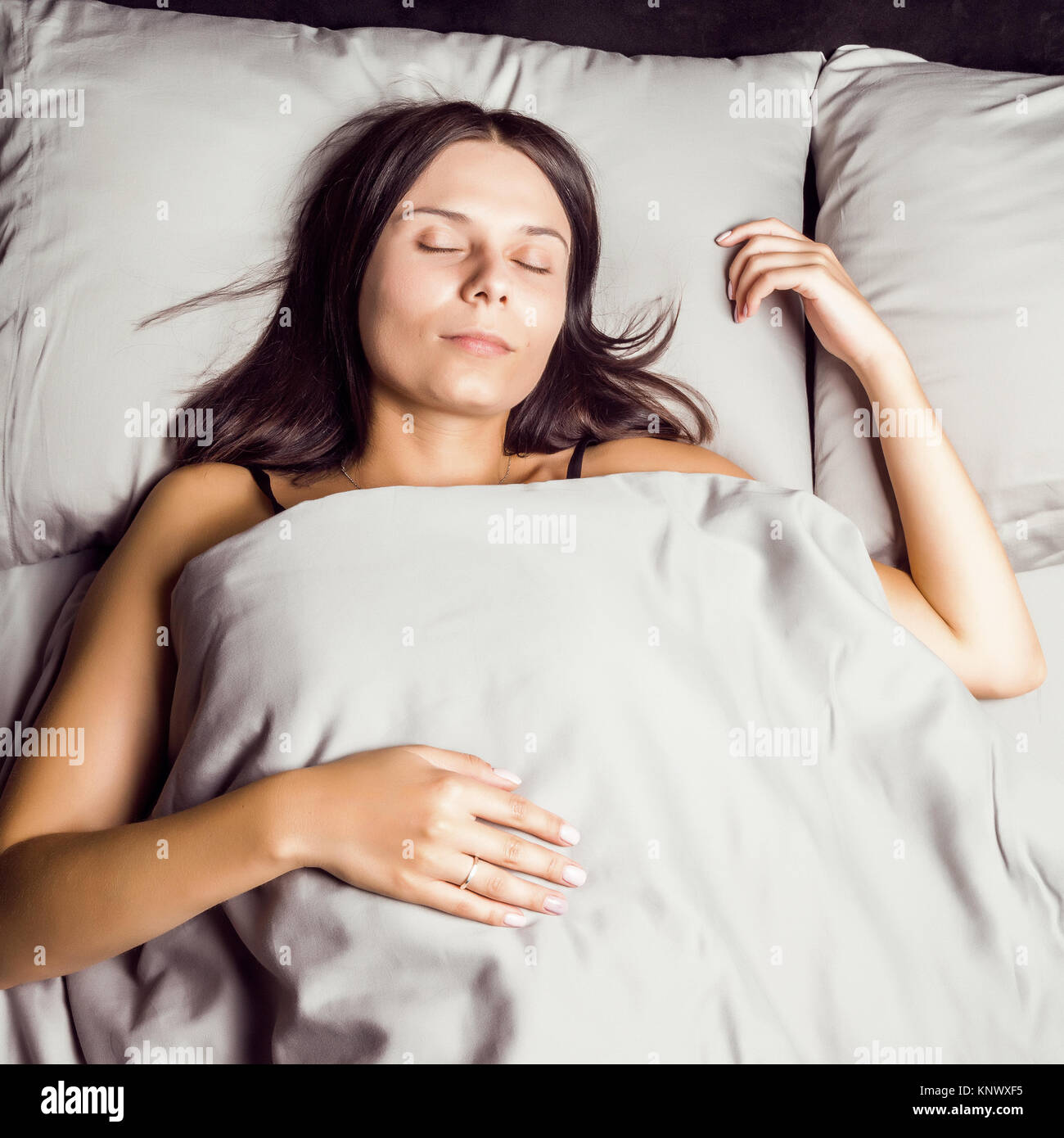 Woman Sleeping In Bed On A Dark Background Stock Photo