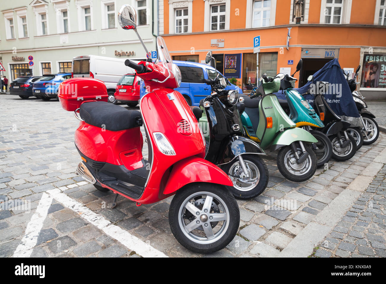 Regensburg, Germany - May 5, 2017: Colorful Vespa scooters stand in a row on a parking lot in old European town Stock Photo