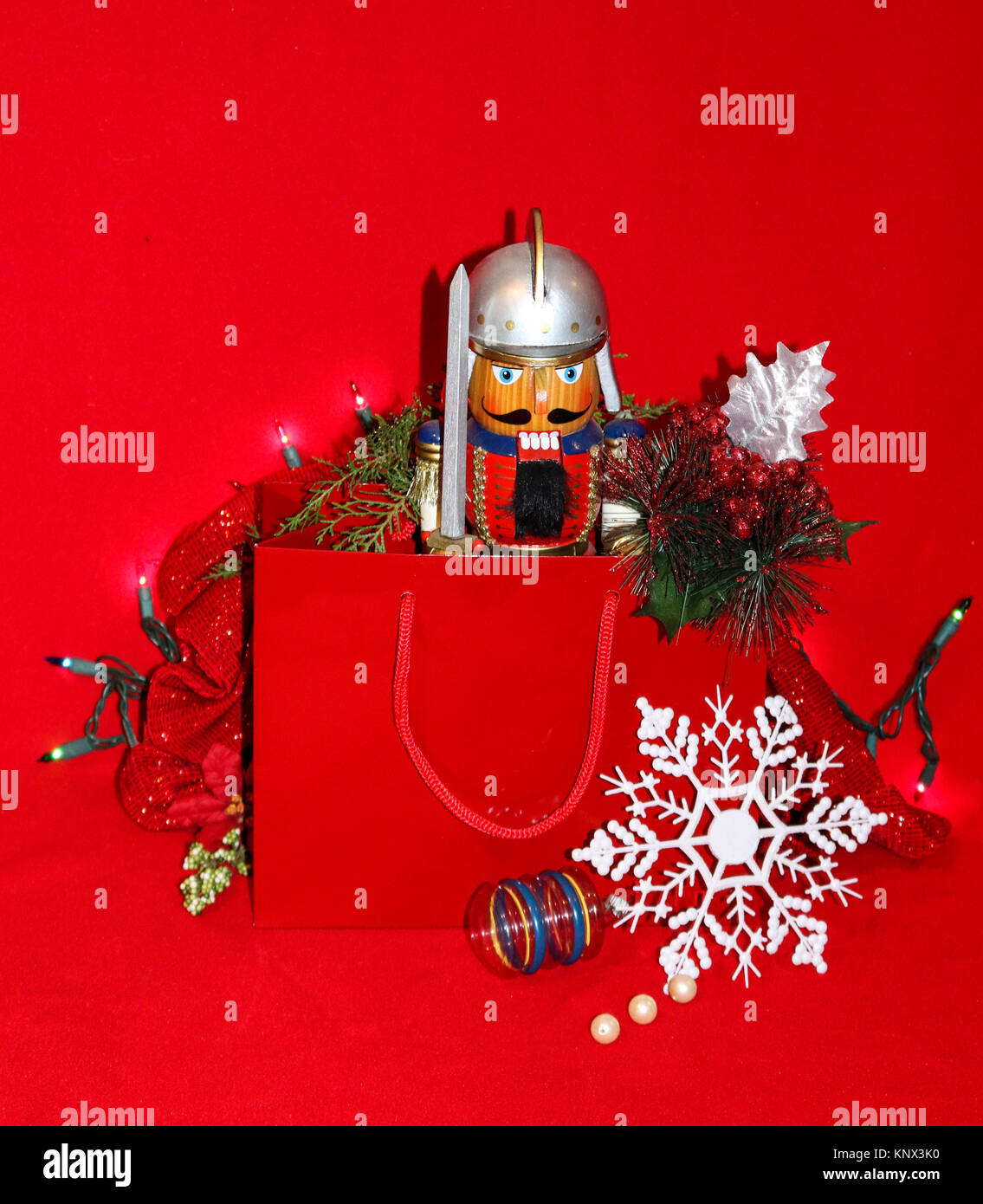 Roman Soldier Nutcracker present in gift bag on red background with snowflake, vintage ornament and Christms lights Stock Photo